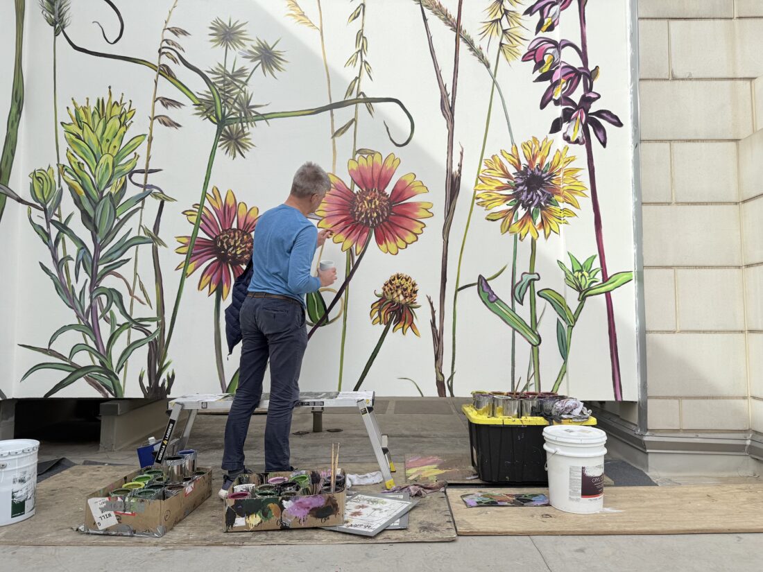 An artist paints a flower mural