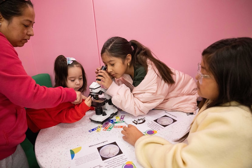Carmen Velazquez helps daughters Emily Velazquez, 1, and Mia Velazquez, 9, of Troop 6701 use...