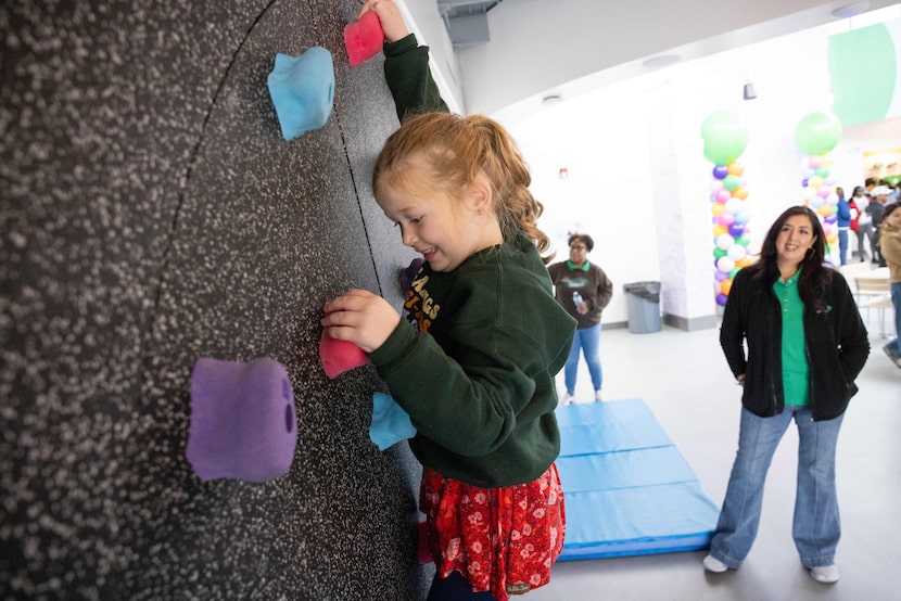 Susanne Elliott, 5, of Troop 1608 uses the rotating rock climbing wall during the public...