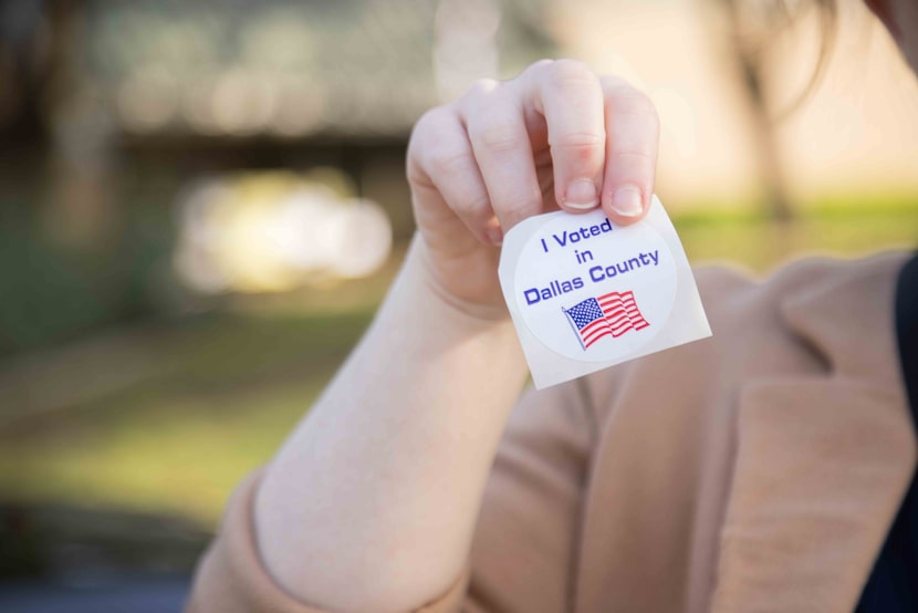 Jennifer Taylor holds up her “I Voted in Dallas County Sticker” after voting during the...