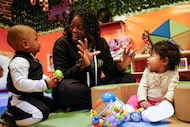 Tamia Miller (center), infant program teacher, talks to 1-year-old Landon Roberts (left) and...