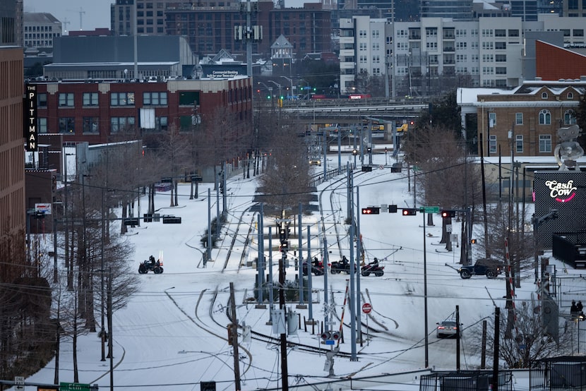 ATVs drive along an icy Gaston Avenue across Good Latimer Expressway on Sunday, Jan. 25,...