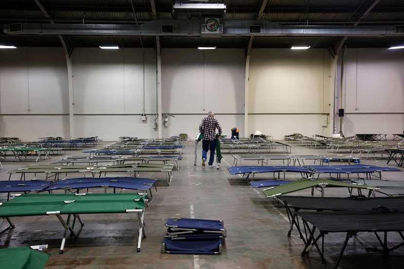 Volunteer Don Carey, 61 of Richardson, left, helps to set up stretchers at the inclement...