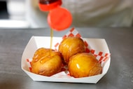 State Fair of Texas concessionaire Abel Gonzales drizzles honey over Deep Fried Butter, the...