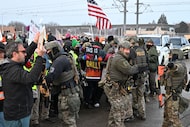 Protesters confront federal agents outside the Bishop Henry Whipple Federal Building,...