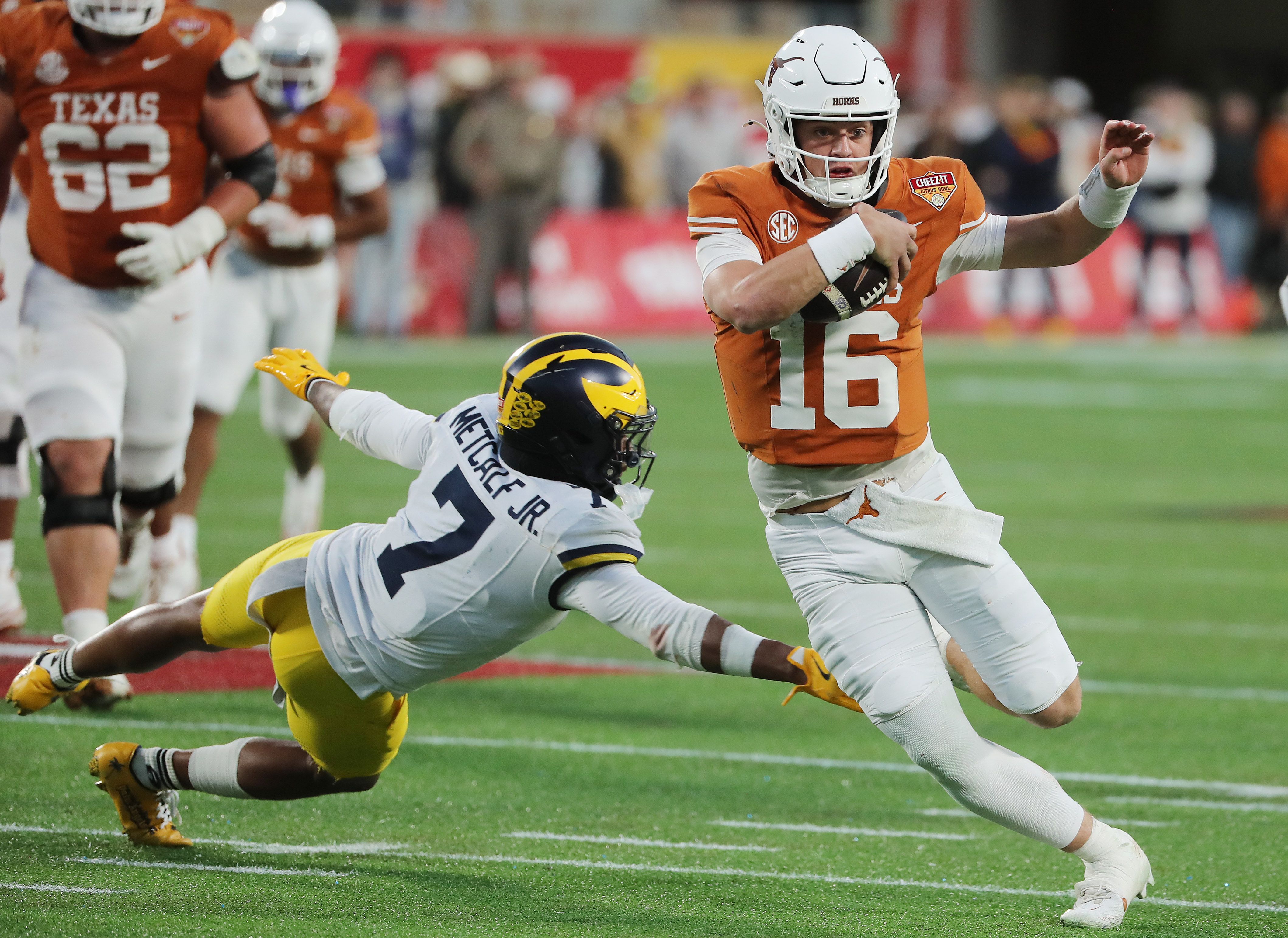 Texas quarterback Arch Manning (16) evadese Michigan defensive back TJ...