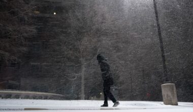 In this Feb. 14, 2021, file photo, woman walks through falling snow in San Antonio. As temperatures plunged and snow and ice whipped the state, much of Texas' power grid collapsed, followed by its water systems. Tens of millions huddled in frigid homes that slowly grew colder or fled for safety. (AP Photo/Eric Gay)
