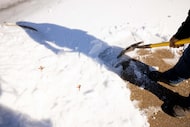 Horacio Tinoco clears his driveway of snow and ice following a winter storm on Wednesday,...
