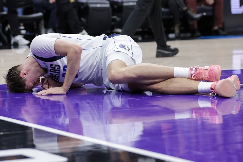 Dallas Mavericks forward Cooper Flagg lays on the court after suffering an injury to his...