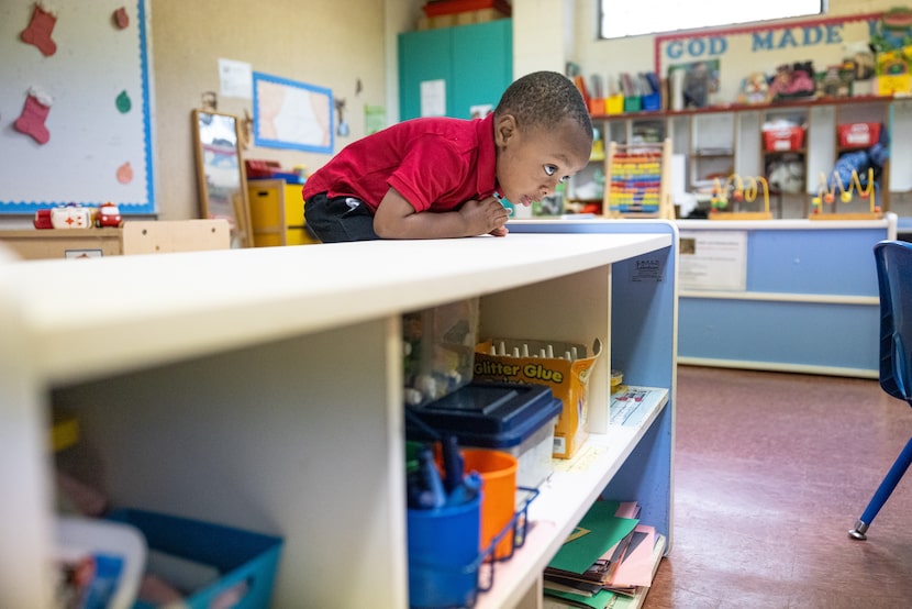 Jayden White, 1, climbs low shelves in the toddlers classroom before morning prayers at Good...