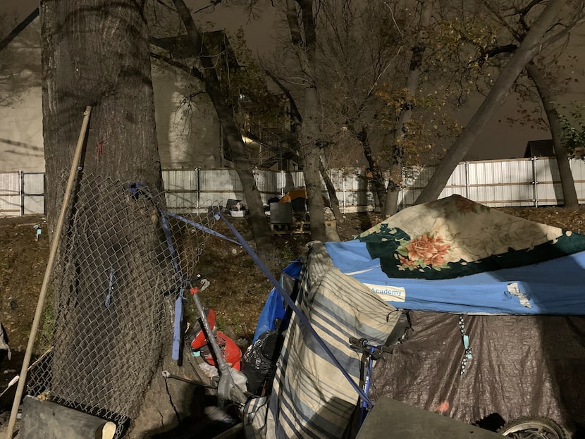 An apartment complex looms over an encampment in northwest Dallas. It's well-lit because...