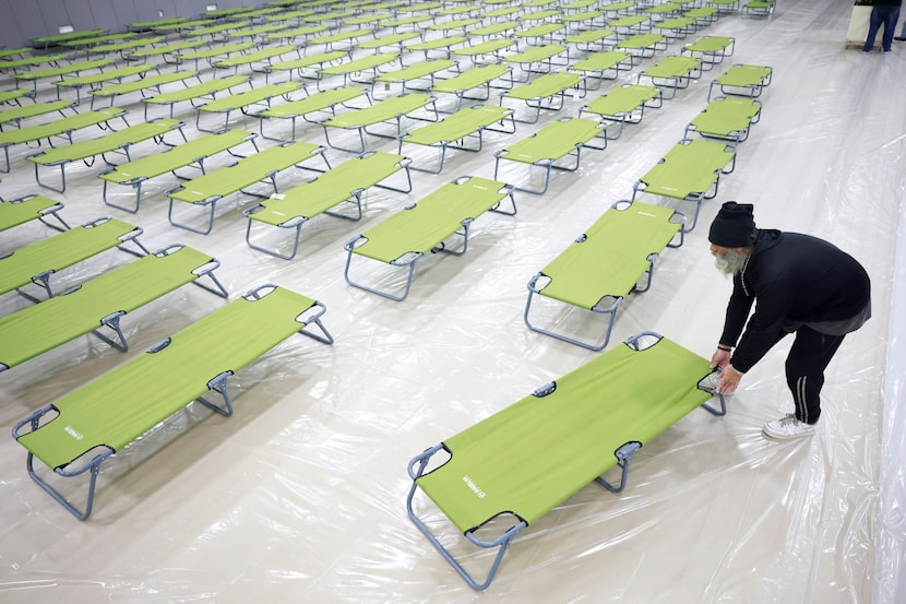 Michael Baker, an unhoused client, helps set up cots at the Plano Overnight Warming Station...