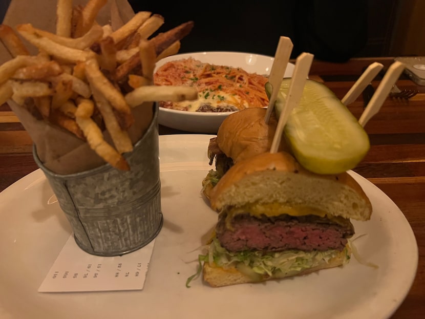 The burger at Neighborhood Services is cut in half before its served alongside russet fries.