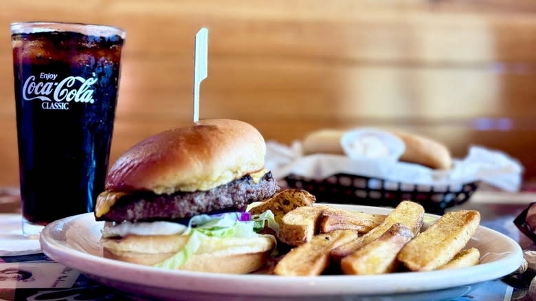 Cheeseburger and fries on a plate with a cup of Coca-Cola