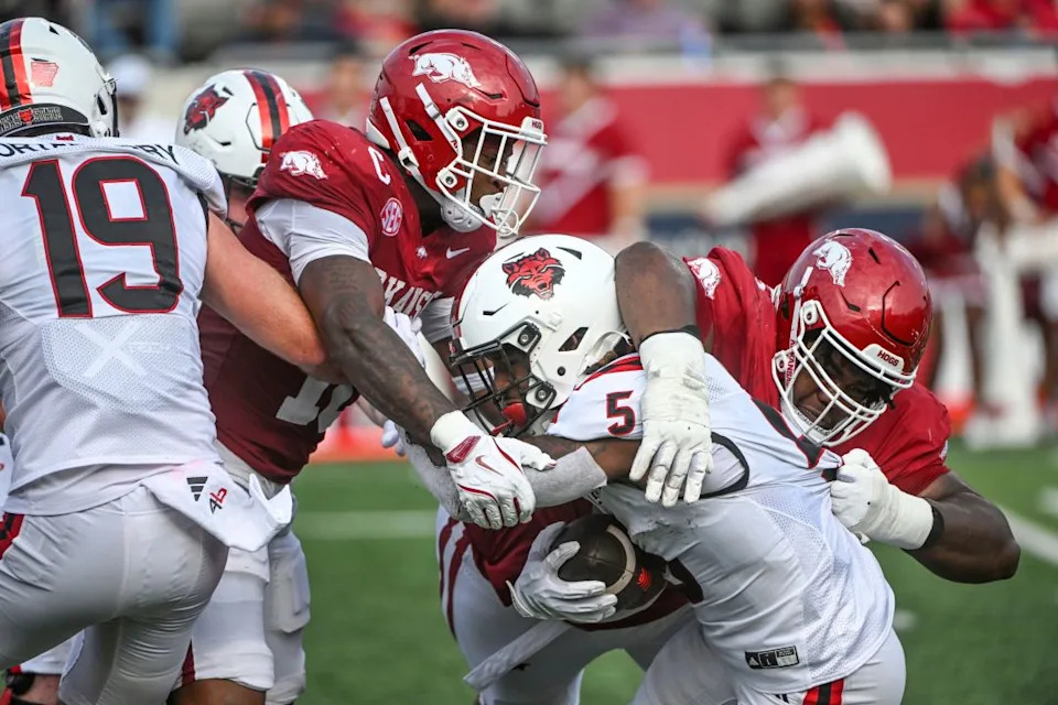 Arkansas defenders Xavian Sorey Jr., left, and Ian Geffrard, right, tackle Arkansas State running back Kenyon Clay (5) during an NCAA football game on Saturday, Sept. 6, 2025, in Little Rock, Ark. (AP Photo/Michael Woods)
