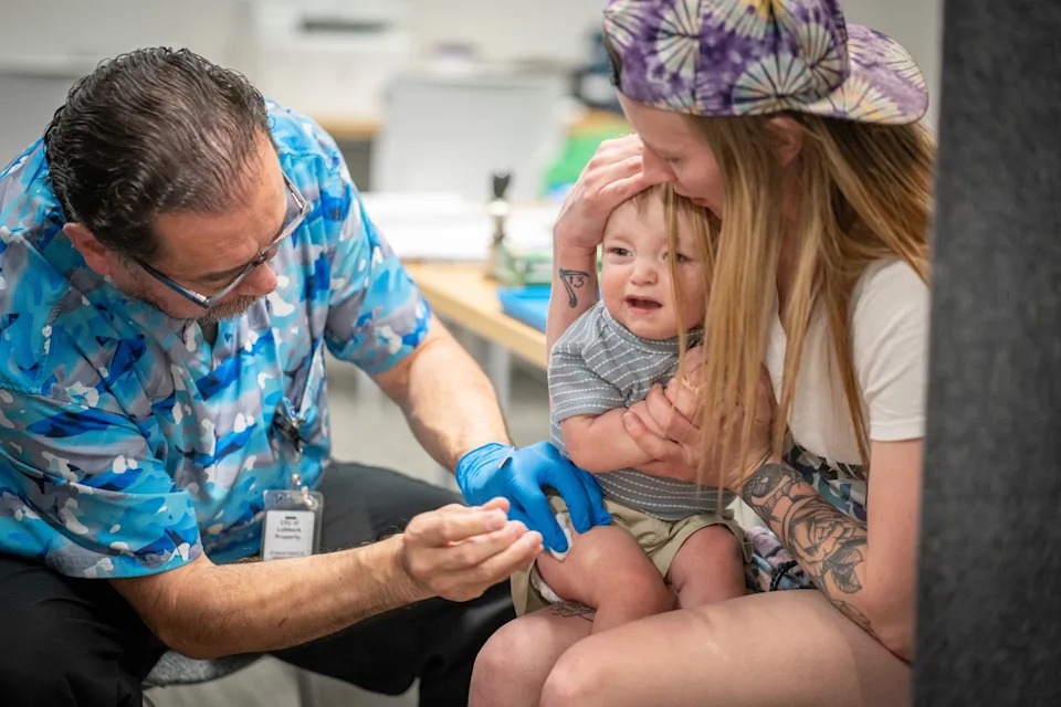 Jan Sonnenmair/Getty Images - PHOTO: One year-old River Jacobs is held by his mother, Caitlin Fuller, while he receives an MMR vaccine from Raynard Covarrubio, at a vaccine clinic put on by Lubbock Public Health Department, March 1, 2025, in Lubbock, Texas.