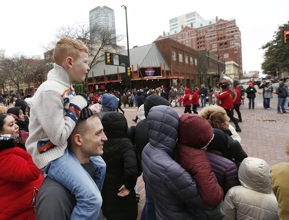 Josh Perkins hold his son Kaiper on his shoulders as the All-Western Parade passes by in downtown Fort Worth on Saturday.