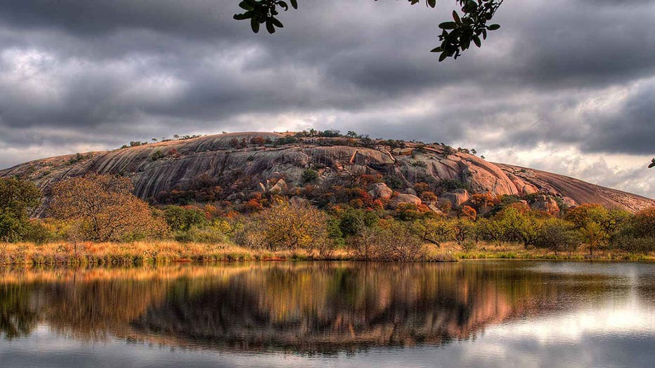 The dome of Enchanted Rock rises above a lake at the Enchanted Rock State Natural Area in Texas.