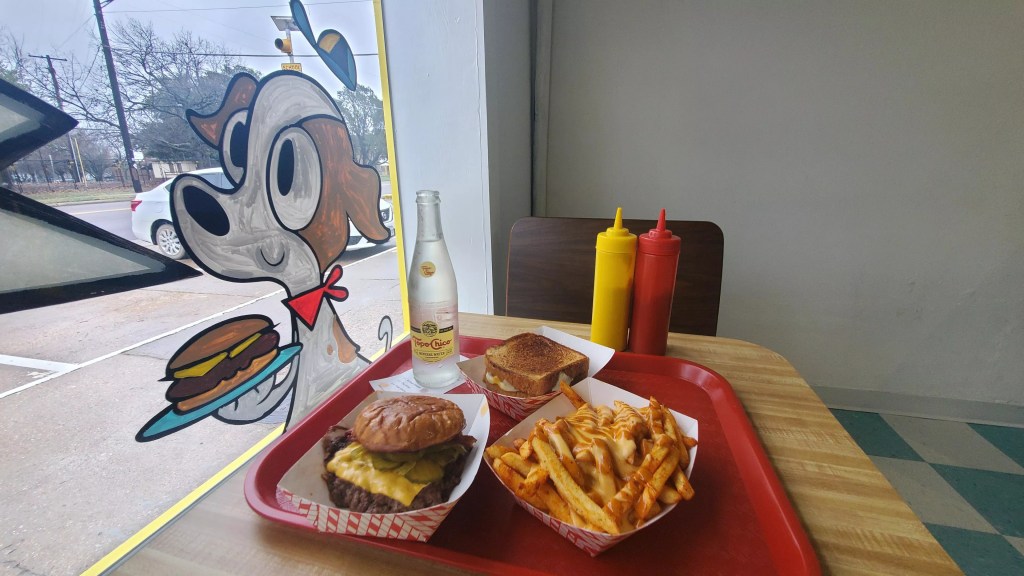 a burger and fries at a window seat at herby's burgers.