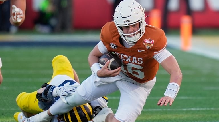 Texas quarterback Arch Manning, right, is stopped by Michigan linebacker...