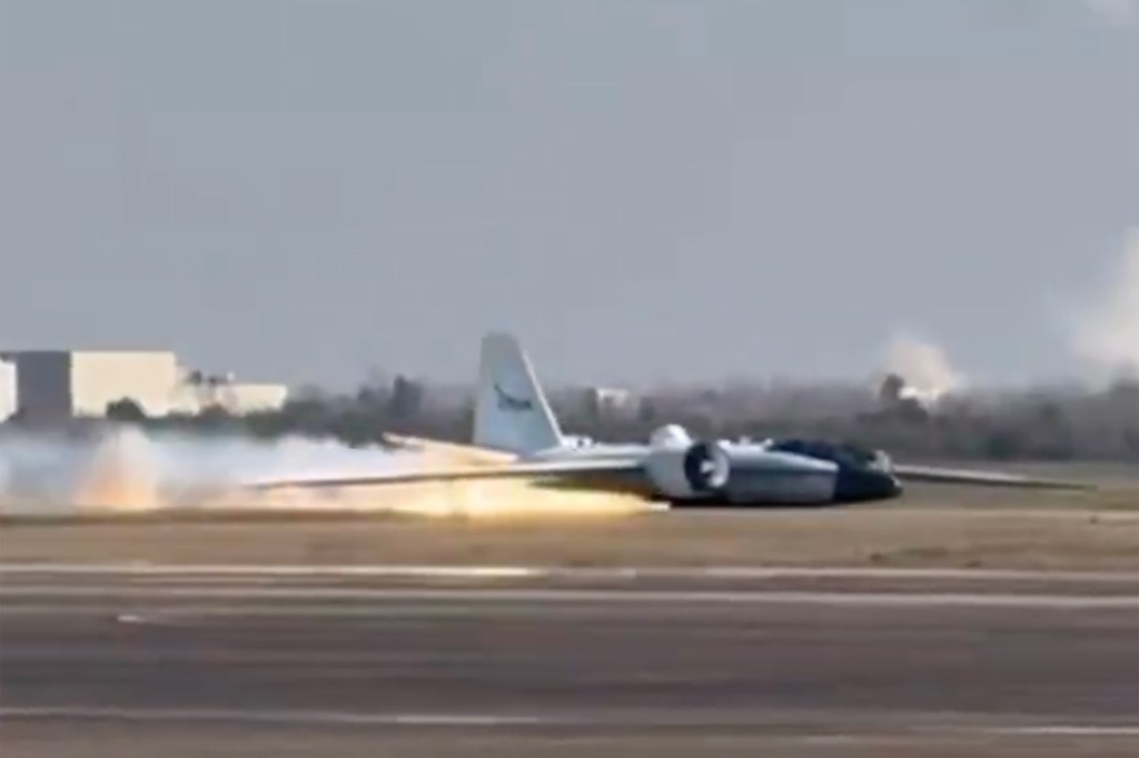 A NASA plane lands on its belly on a runway, with flames and smoke coming from beneath it