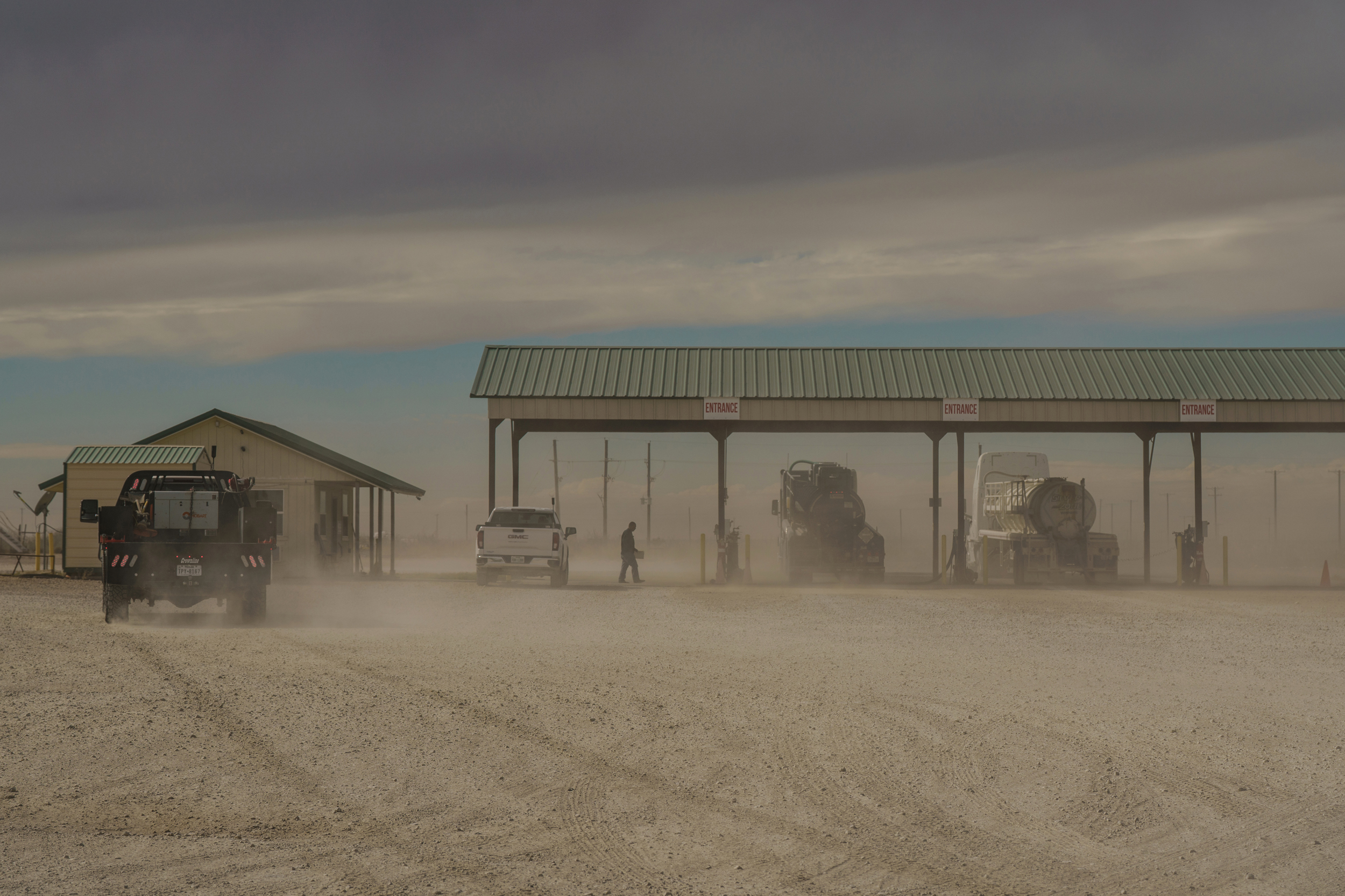 A man walks between trucks at a saltwater disposal site on the outskirts of Midland, Texas, on Nov. 20, 2025. Credit: Paul Ratje/Inside Climate News