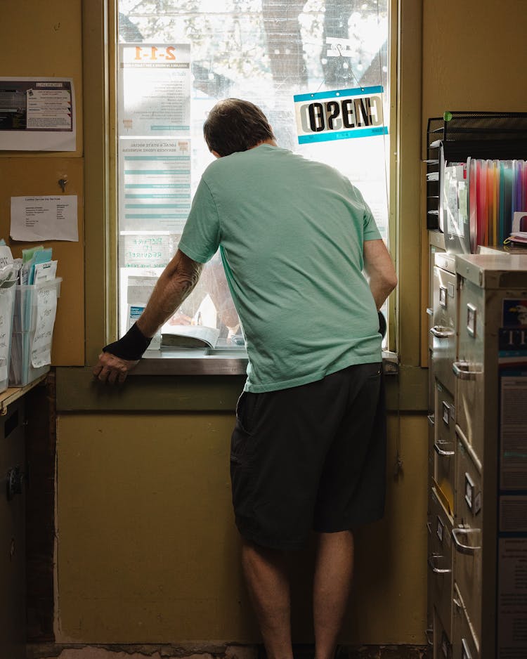 A volunteer speaks to a client from inside the mailroom.
