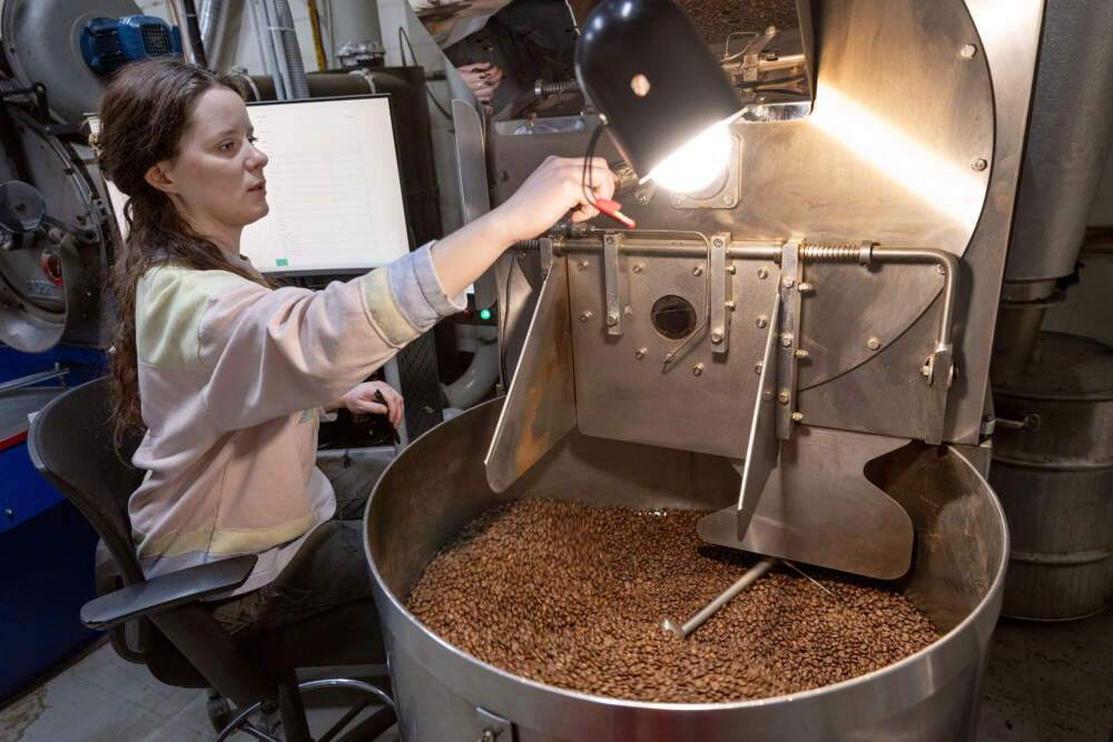 Roast technician Elyse Barber checks on the beans in a coffee roaster at the George Howell roastery in Acton, Mass. (Robin Lubbock/WBUR)