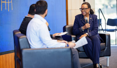 woman in blue suit wearing glasses holding a microphone