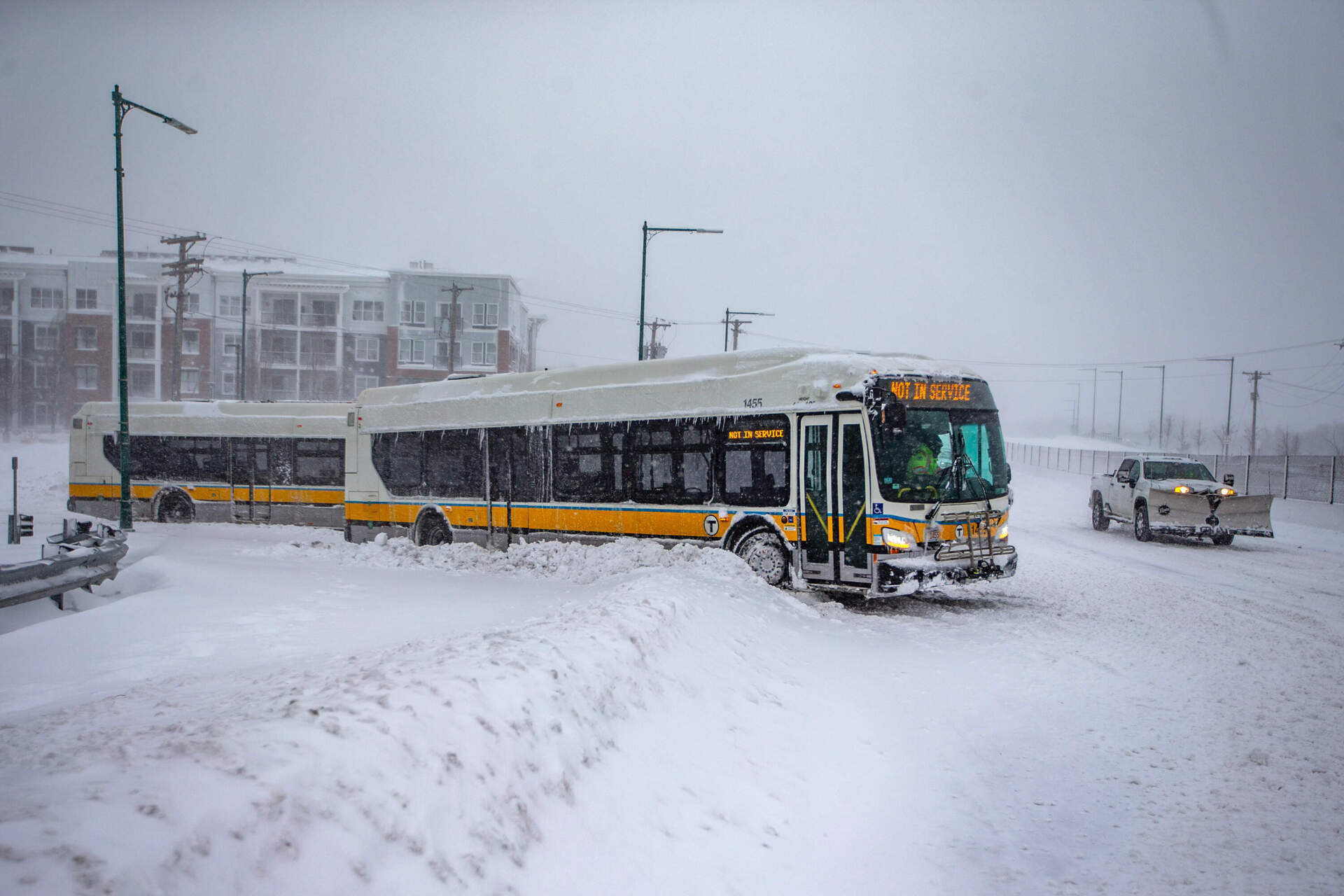 Two MBTA buses stuck in the deep snow getting onto Revere Beach Parkway by Wellington Station in Medford. (Jesse Costa/WBUR)