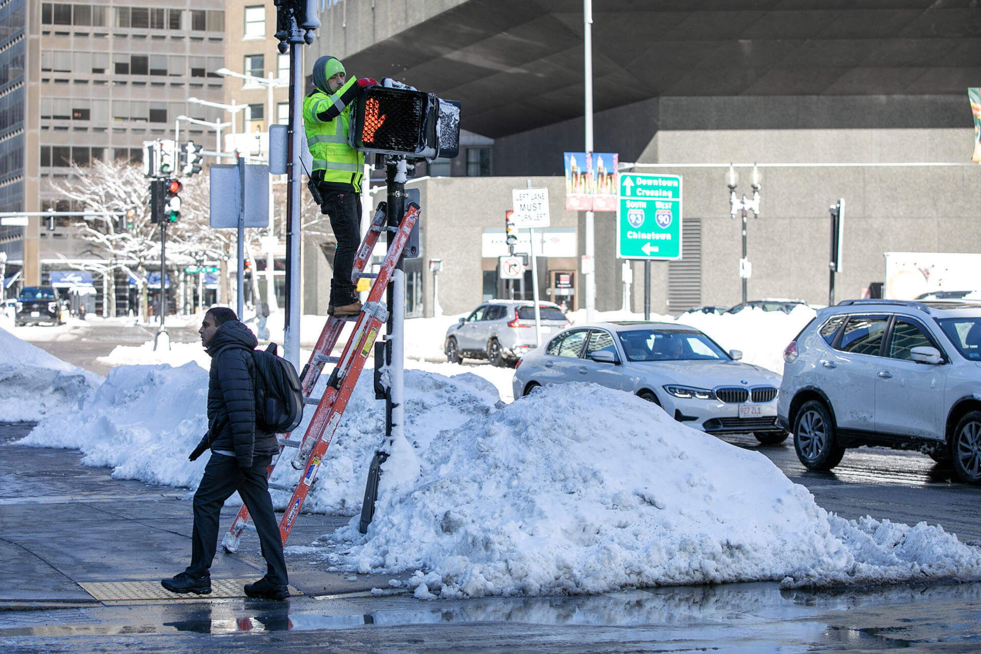 A technician clears and fixes a pedestrian crossing light by South Station in Boston, as the city clears up after the nor'easter. (Robin Lubbock/WBUR)