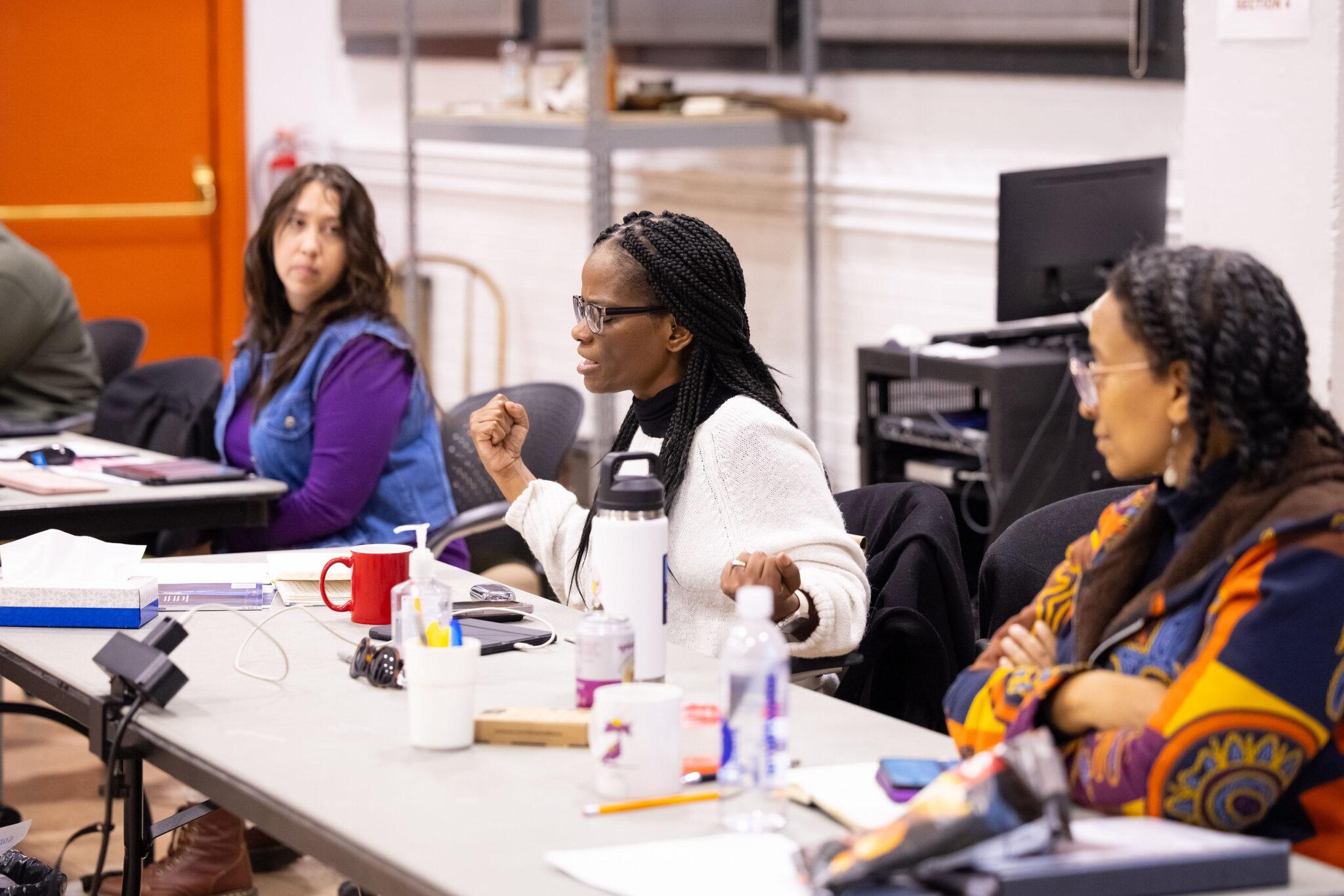 Woman sits at table giving directions.