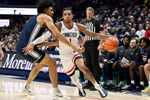 UConn guard Solo Ball (1) is guarded by East Texas A&M's Michael Folarin, left, in the first half of an NCAA college basketball game, Friday, Dec. 5, 2025, in Storrs, Conn. (AP Photo/Jessica Hill)