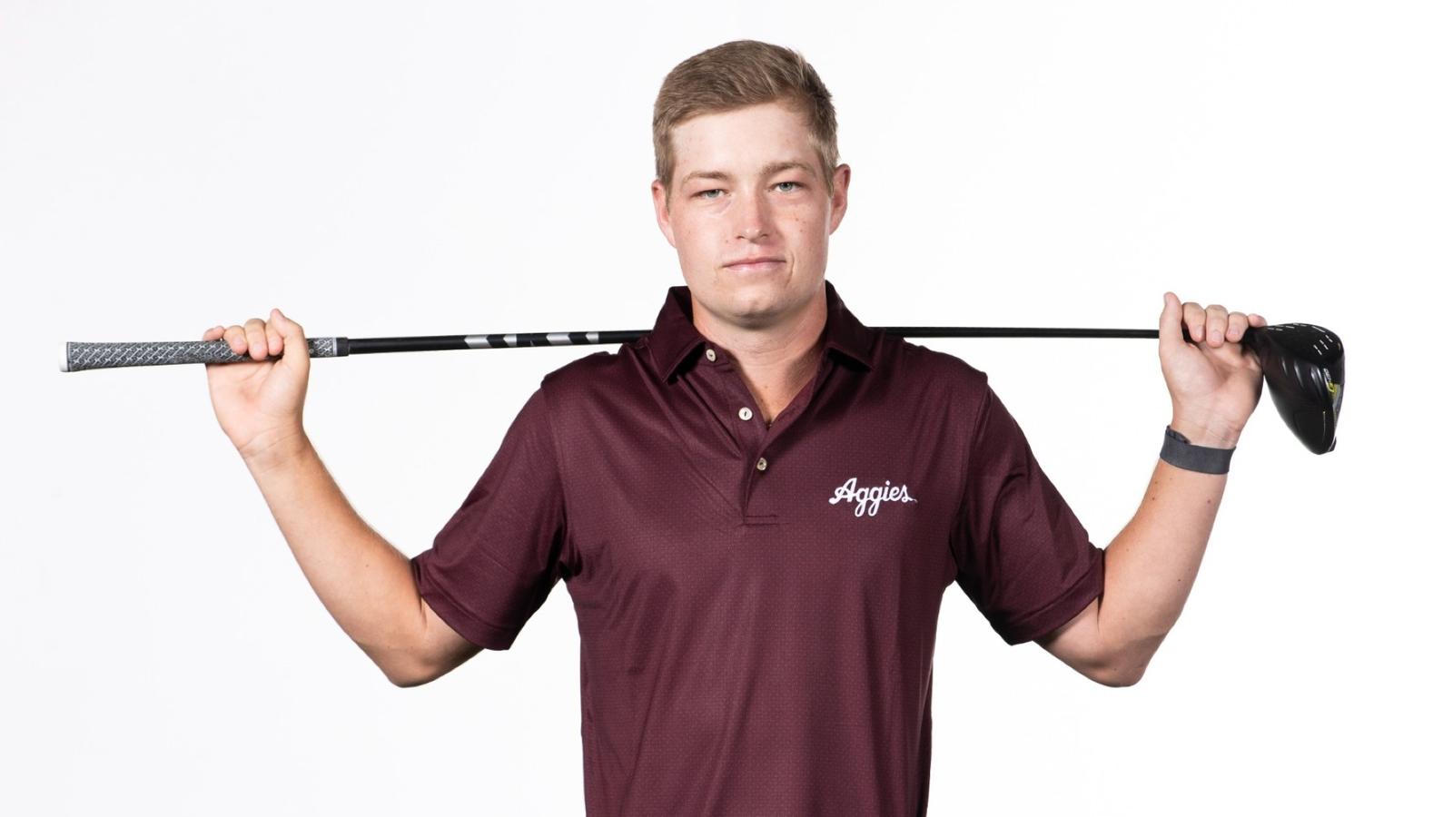 Aaron Pounds poses arms folded in front of a Lone Star Flag themed Texas A&M backdrop