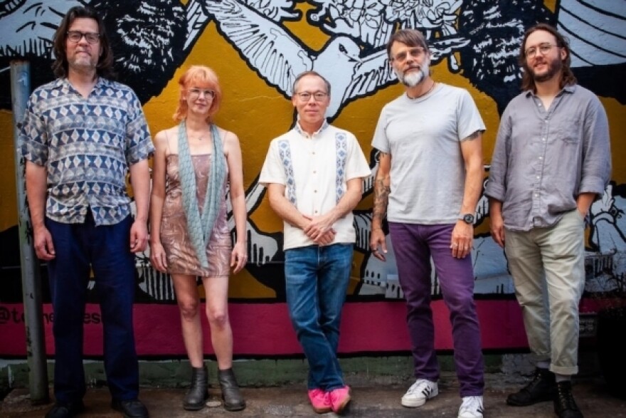 Members of rrunnerrss pose for a photo against a mural