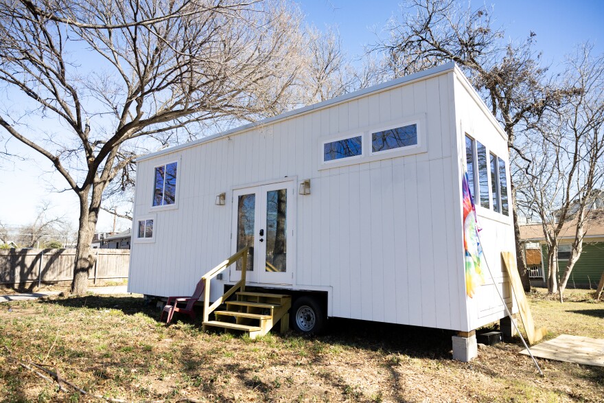 A white tiny home sits on land.