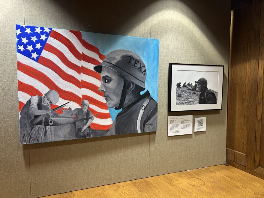 A photo of a painting of a soldier looking to the left in profile, with an American flag waving behind his head. Next to the large painting is the smaller black and white photograph the painting is based on,