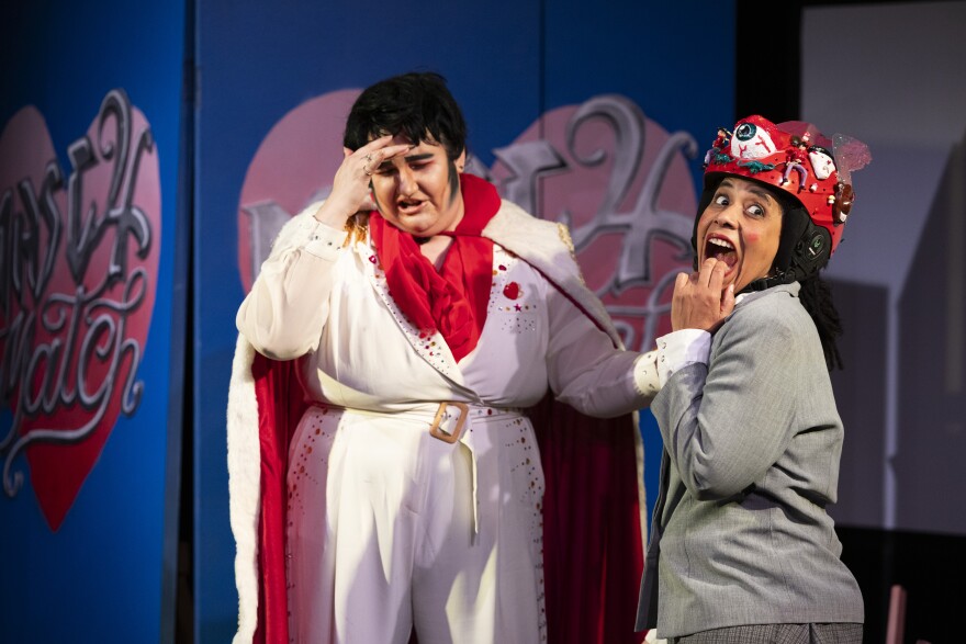 A person dressed as Elvis performs with a person wearing a red hat dressed as Pee Wee Herman.