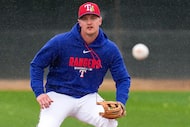 Texas Rangers third baseman Josh Jung participates in a fielding drill as rain falls during...