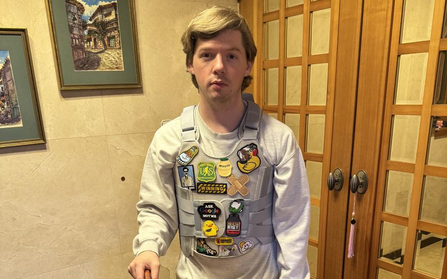 A man with a leg injury stands with the assistance of a cane and a large black brace around his right knee.