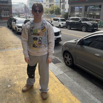 A man with a leg injury standing on a sidewalk with a large black brace around his right knee.