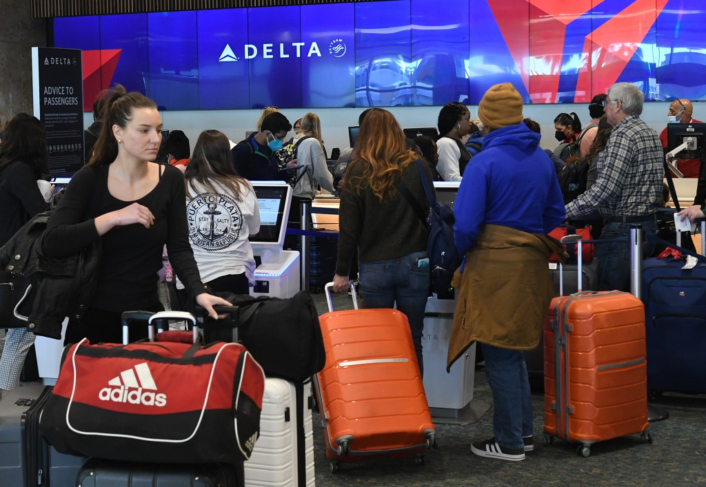 Travelers wait in line at a Delta Airlines ticket counter at Orlando International Airport.