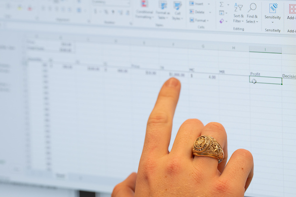 a finger pointing to a line on a spreadsheet