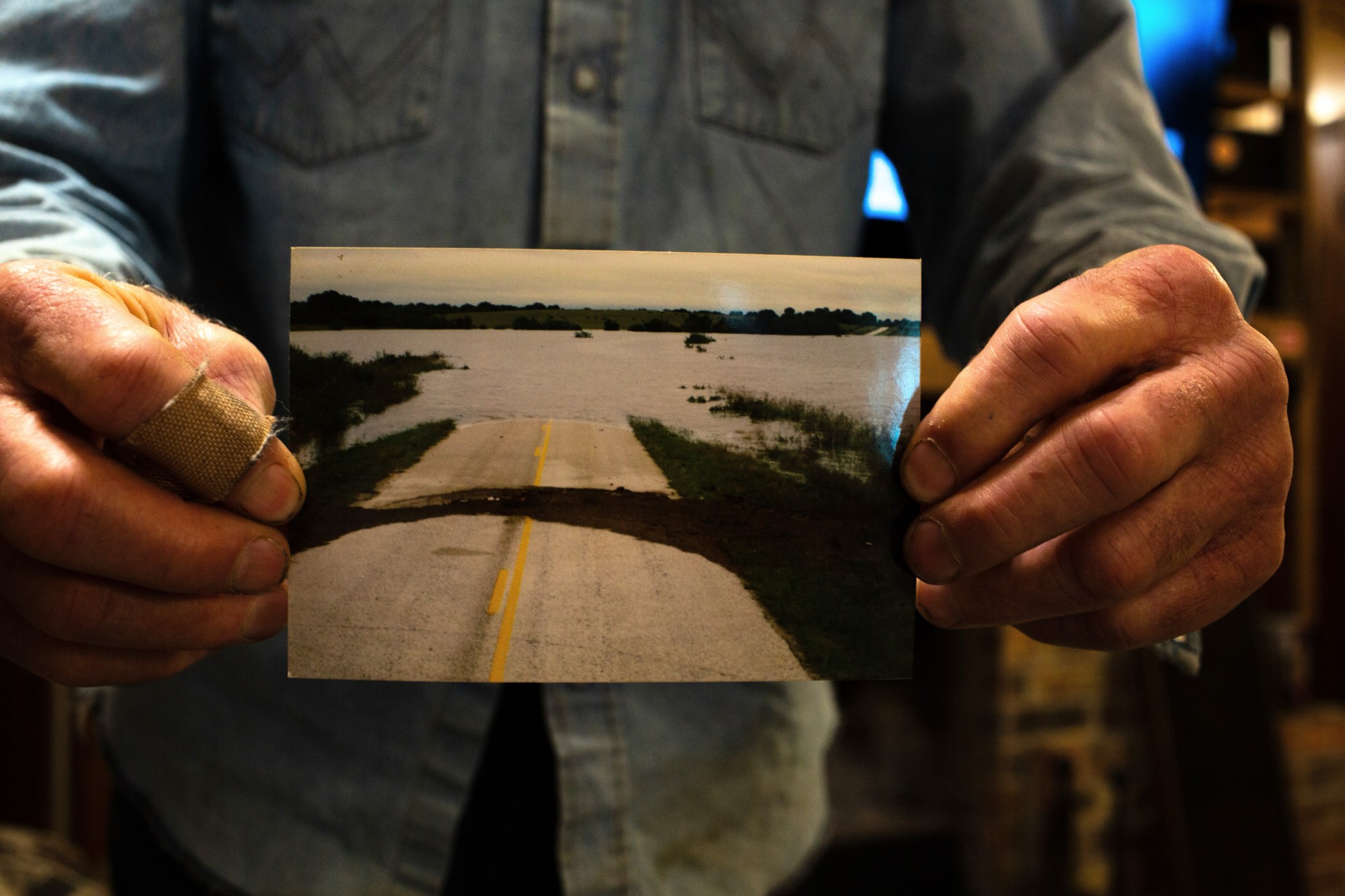 Blake Muir displays a photo of floodwater covering Highway 183 in Gonzales County in October 1998.