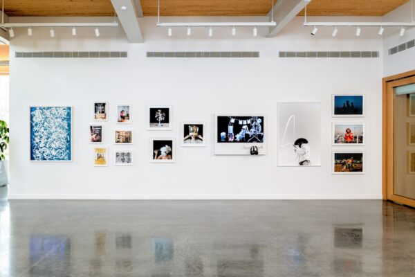 An installation view of artworks hung a white wall in an office building lobby.