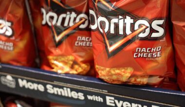 Bags of PepsiCo's Frito-Lay Doritos nacho cheese tortilla chips are displayed alongside packaged foods for sale at a warehouse grocery store in Hawthorne, California.