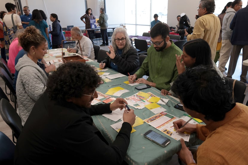 Attendees converse while personalizing postcards to send to community residents to promote...