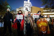 Demonstrators hold signs and hands during a moment of silence for those killed by ICE during...