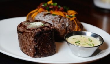 Steak, baked potato and seasoned butter on a white plate.
