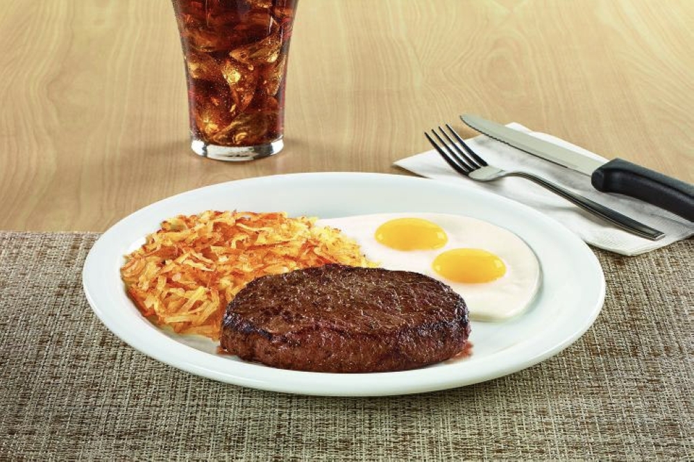 An image the steak and eggs on the menu.